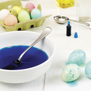 Použitím a fork, stir the oily liquid to create swirls on the surface. Holding a dyed egg in your hand, place it in the mixture and roll the whole surface of the egg around once to pick up the oil streaks. Pat the excess liquid with a paper towel and allow to dry.